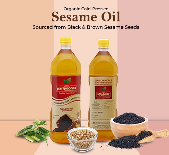 Two bottles of pure organic cold-pressed sesame oil with black and brown sesame seeds in front.